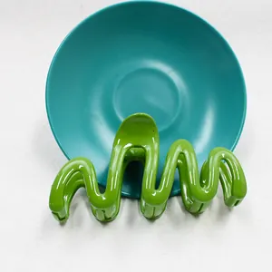 Dettaglio di un fermaglio per capelli ondulato verde brillante con finitura lucida
