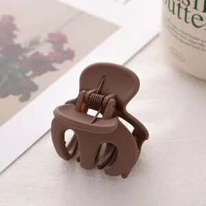 Détail d'une pince à cheveux mate marron sur magazine avec ressort apparent
