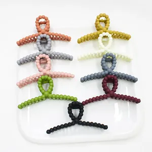 Close-up of matte beaded hair claws in 9 assorted candy colors on a ceramic tray