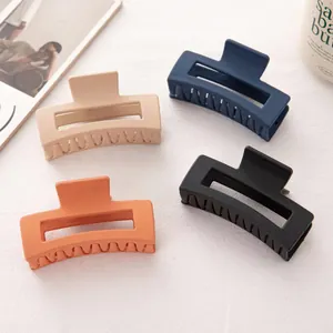 Détail de quatre pinces à cheveux rectangulaires mates en beige, orange, bleu et noir