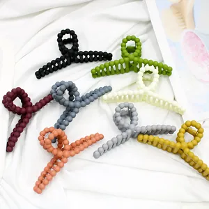 Detail of 8 matte candy-colored twisted hair claws arranged on white fabric background