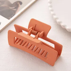 Détail d'une pince à cheveux rectangulaire orange mate avec un ressort métallique robuste