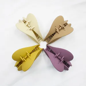 Dettaglio di quattro mollette per capelli opache a cuore in beige, marrone, giallo e viola