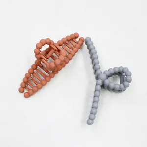 Close-up of matte bubble texture claw clips in brick red and grey for long hair