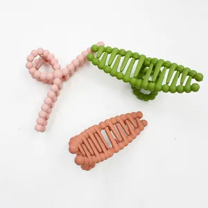 Detailed view of matte hair claws in pink, olive green, and caramel with bead design