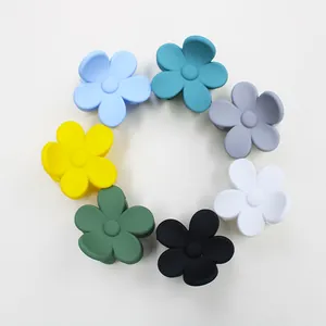 Flat lay of small matte five-petal flower hair claws in seven assorted pastel colors