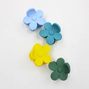 Close-up of four matte macaron floral hair claws in blue, yellow, and green colors
