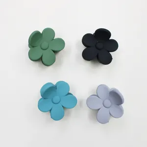 Detailed top view of four small matte flower hair claws in green, black, blue and purple