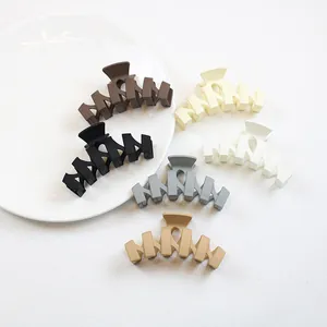 Détail de six grandes pinces à cheveux mates aux tons neutres et design évidé