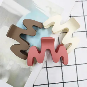Detailed view of matte texture wavy hair claws in brown, cream and pink colors