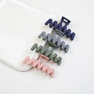 Détail de quatre grandes pinces à cheveux mates en bleu marine, gris, olive et rose