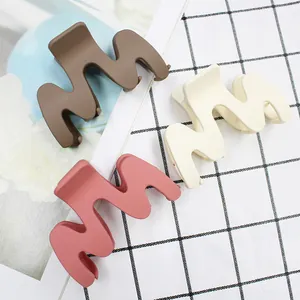 Three-piece set of large wavy matte claw clips in brown, cream, and coral pink colors