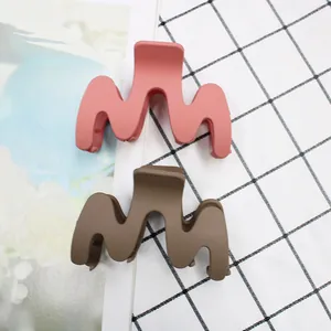 Detail view of wavy matte claw clips in coral pink and dark brown for daily hairstyles