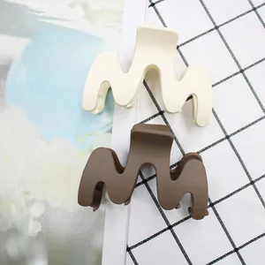 Detail of matte finish and M-shape design on large beige and brown hair claws