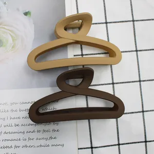 Detail view of matte apricot and dark coffee cross twist claw clips in a two-piece set