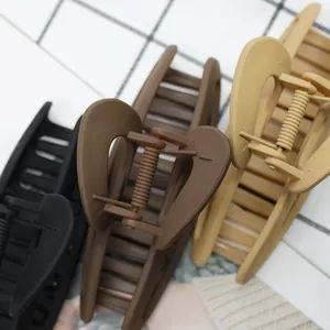 Close-up of matte hair claw clips in black, coffee, and beige with metal springs