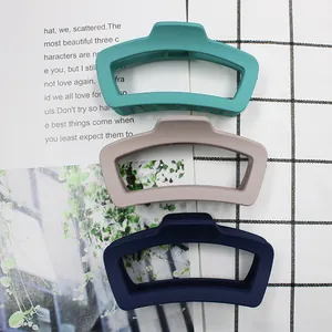 Tre pinze per capelli geometriche opache in verde scuro, kaki e blu navy su sfondo a scacchi