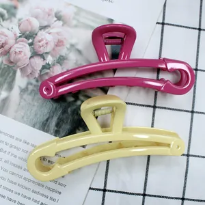 Detail of candy-colored safety pin hair claws in rose red and cream yellow matte plastic