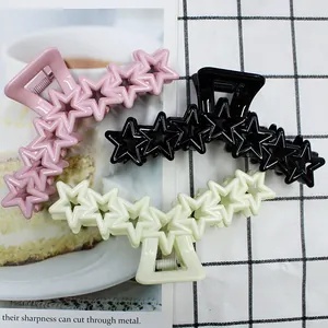 Three-piece set of star-shaped hair claws in pink, black, and beige with metal springs