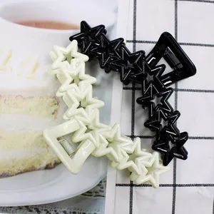 Close-up of star-shaped hair clips in black and cream with a glossy resin finish