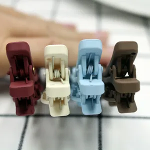 Detail of four matte colorful duckbill hair clips showing the metal spring structure