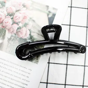 Detail of high-gloss black resin hair claw clip in a unique safety pin design