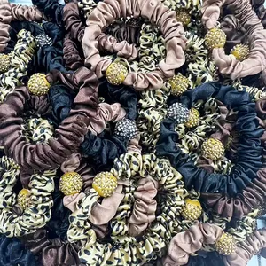 Close-up of leopard print and satin scrunchies featuring sparkling rhinestone spheres