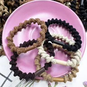 Detail of wavy spiral hair ties in earth tones with smooth tube buckles in a pink tray