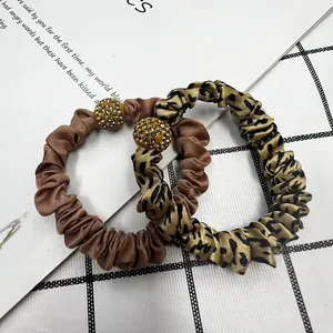 Close-up of leopard print and satin scrunchies with sparkling rhinestone gold beads