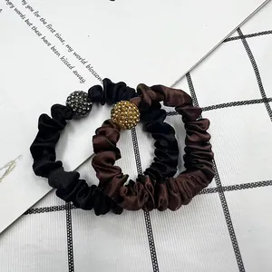 Detail of satin scrunchies in black and brown with sparkling rhinestone ball accents