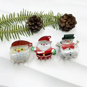 Close-up of glittery Santa and Snowman hair clips on white textured background