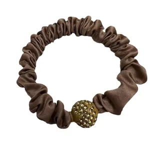 Brown silk scrunchie with rhinestone-studded gold ornament in minimalist Korean style