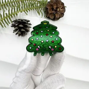 Close-up of glittery green Christmas tree hair claw clip with cute face and star