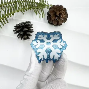 Detailed view of a blue glitter snowflake hair claw clip with white festive patterns