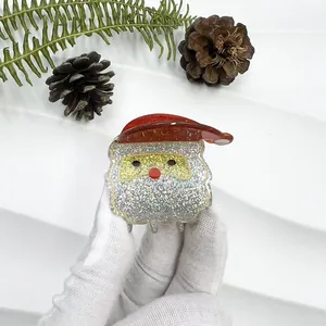Detail of glittery Santa Claus hair claw clip held in hand with festive Christmas decor
