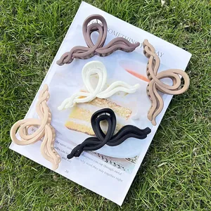Set of 5 matte acrylic hair claw clips in cream and brown tones on a magazine and grass