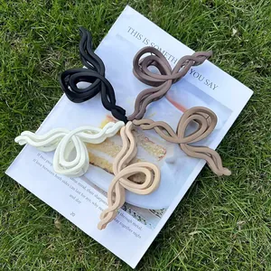 Set of four minimalist wave-shaped acrylic hair claws in matte neutral cream tones on grass