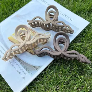 Three matte cream and brown wavy acrylic hair claws set on a magazine background