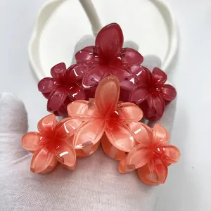 Dettaglio delle mollette per capelli a forma di fiore in resina lucida rossa e arancione