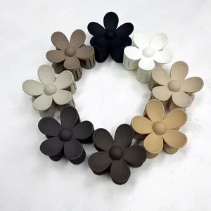 Otto mollette per capelli a forma di fiore opaco in toni neutri disposte in cerchio su marmo