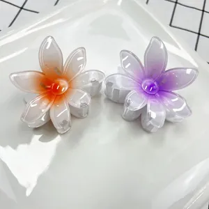 Gros plan de pinces à cheveux fleur dégradé orange et violet sur plateau blanc