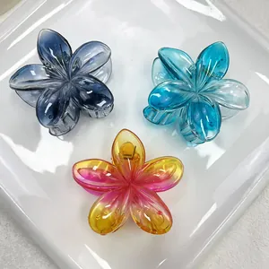 Détail de trois pinces à cheveux fleur en résine dégradée bleue et rose sur plat