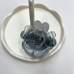 Pinza per capelli a fiore grigio traslucido con petali a forma di cuore su piatto bianco