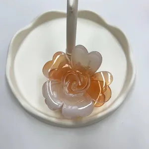 Dettaglio del fermaglio a rosa in resina ambrata su un vassoio di nuvola in ceramica