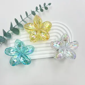 Close-up of plumeria hair claws with holographic finish on a white textured stand