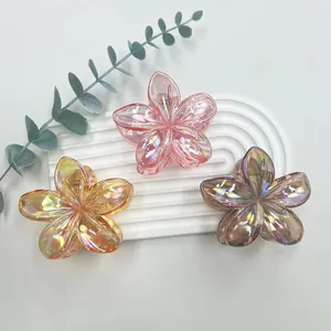 Close-up of three iridescent plumeria flower hair clips on a white display stand