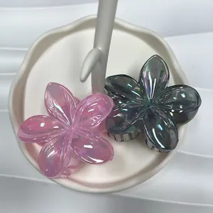 Macro shot of iridescent plumeria hair claws in pink and teal on a white ceramic tray