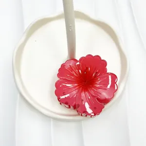 Dettaglio di un fermaglio per capelli a fiore rosso traslucido con petali lucidi eleganti