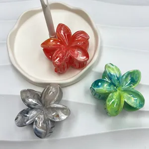 Dettaglio di fermagli per capelli a fiore di plumeria con sfumature effetto marmo