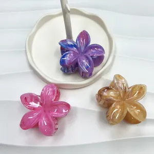 Dettaglio macro di tre mollette per capelli a plumeria marmorizzata in vari colori sfumati